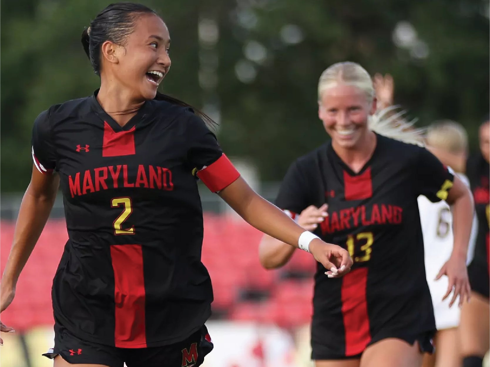 Members of the Maryland women's soccer team smile and laugh while running on the field