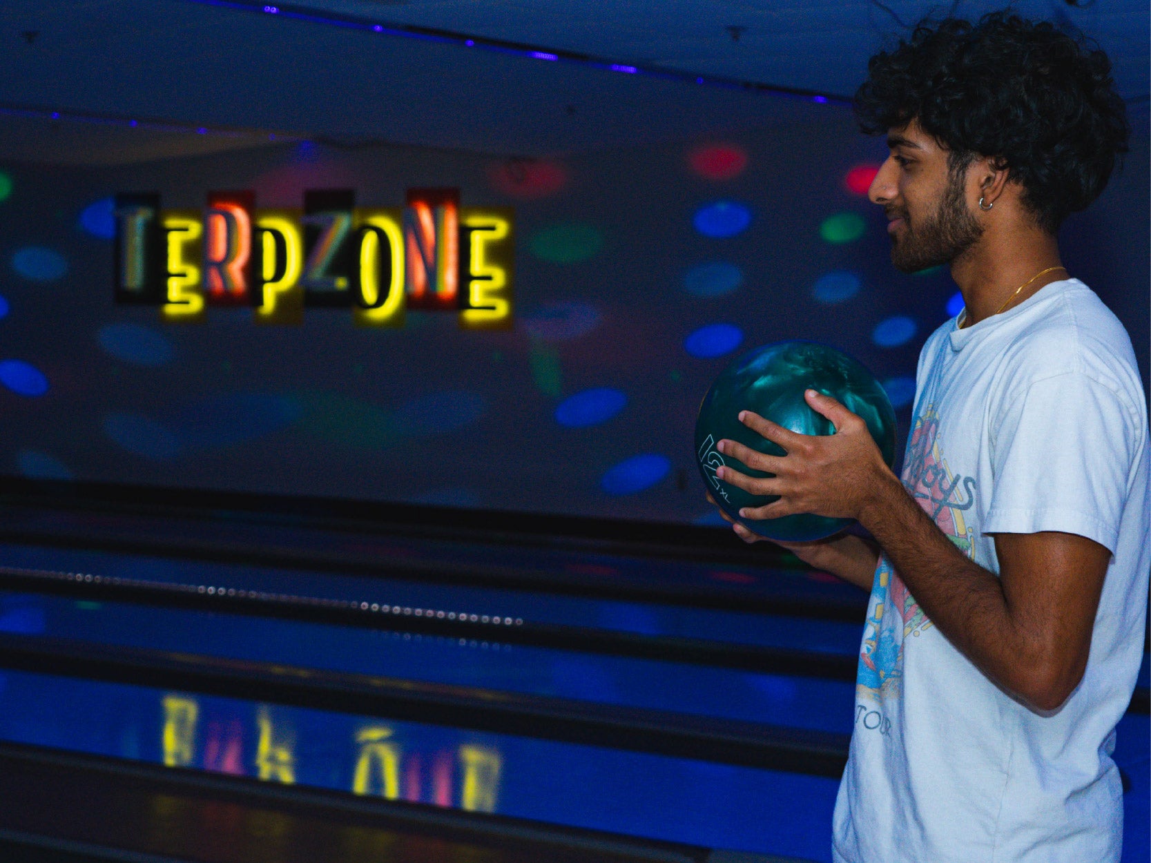 A UMD student holds a bowling ball under black lights in the TerpZone