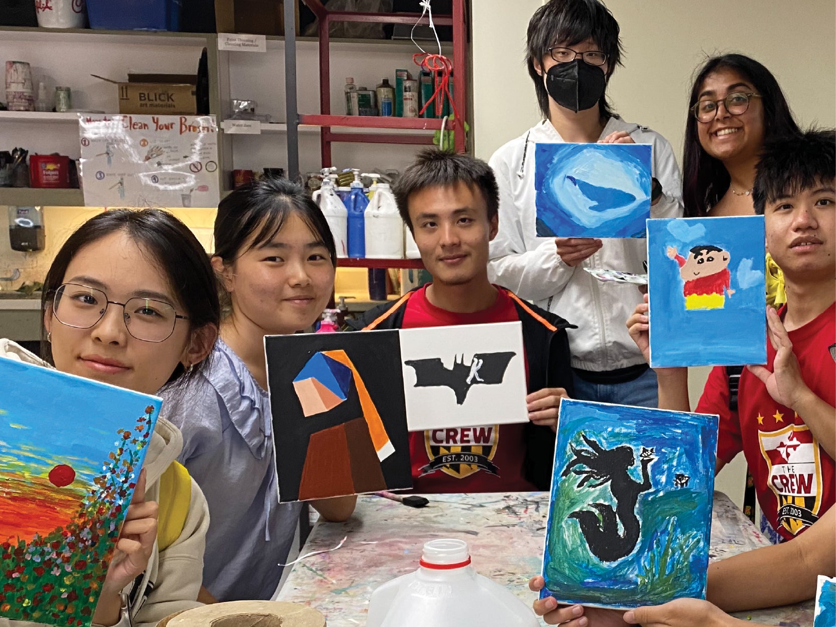 A group of UMD students hold up painted canvases in STAMP's Studio A
