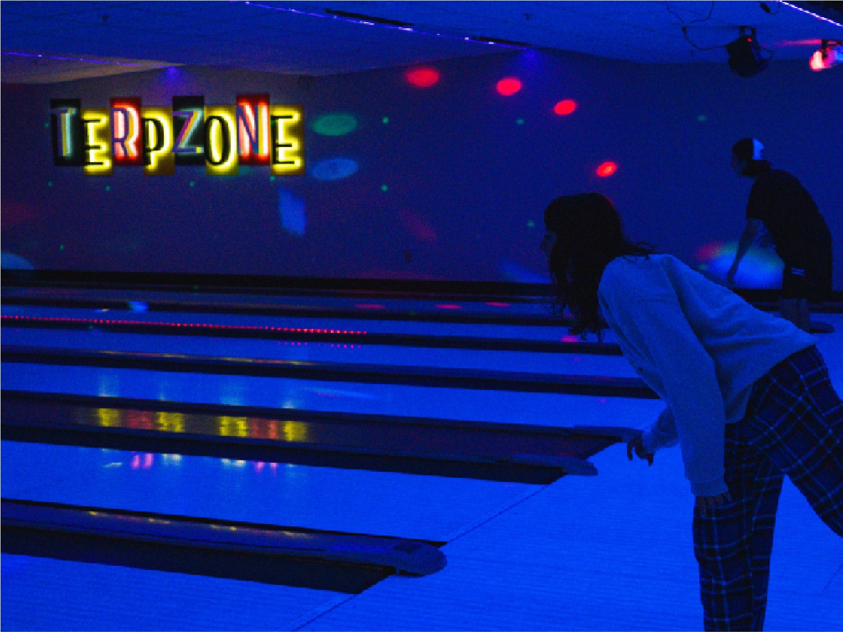 A photo of 2 students bowling in TerpZone during a Glow Bowling event.
