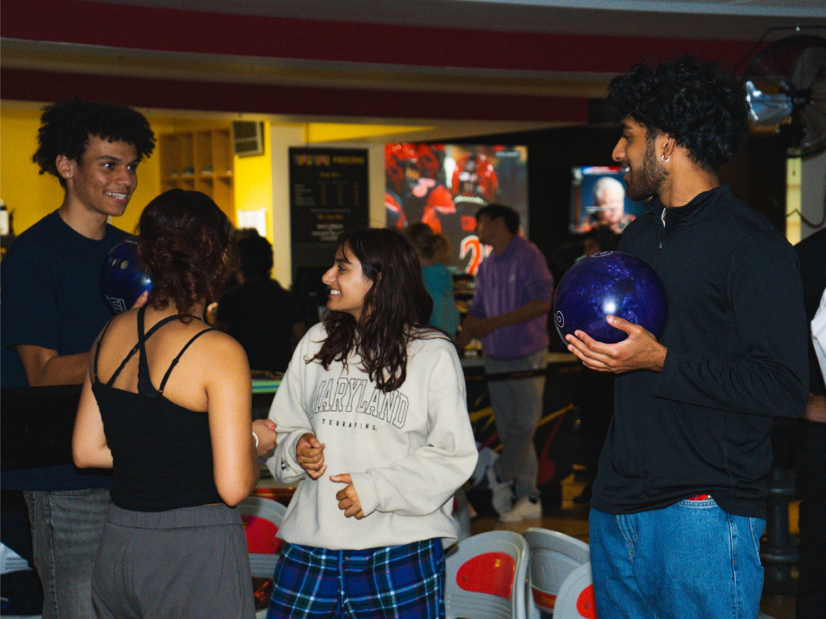 A photo of students in Terpzone. Two students are holding bowling ballsand engaing with two other students.