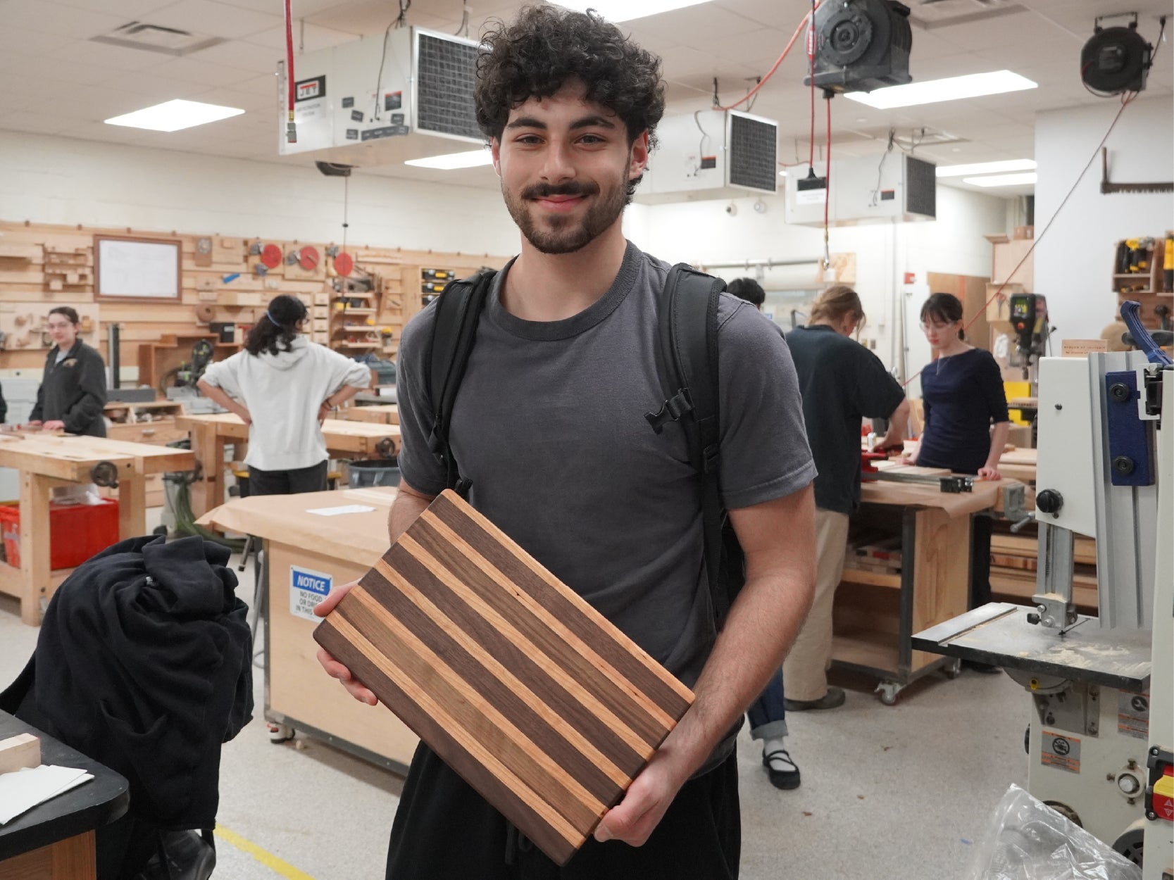 A photo of a student holding a cutting board project made in the Keystone woodshop.