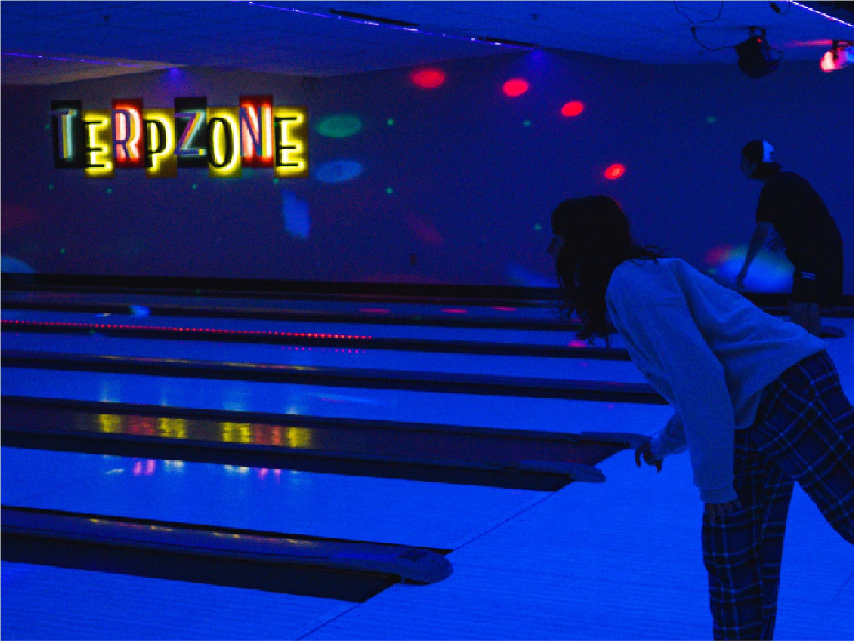 A photo of two students bowling in TerpZone during a Glow Bowling event.
