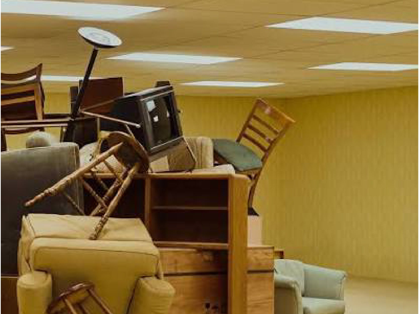 A promotional photo for the movie "Backrooms". The photo shows a large pile of furniture stacked all the way to the ceiling.
