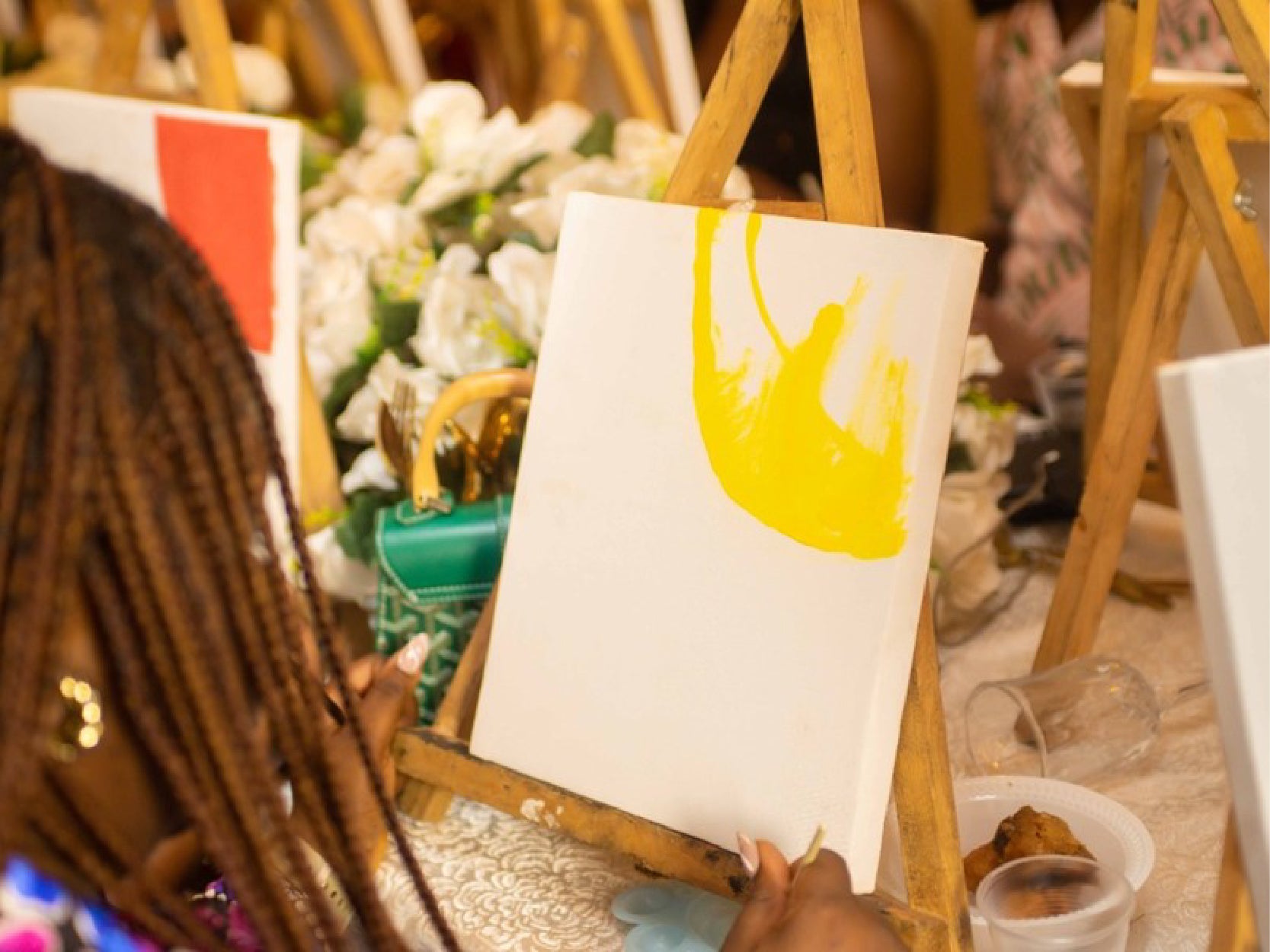 A close up photo of a woman painting with yellow paint on a canvas