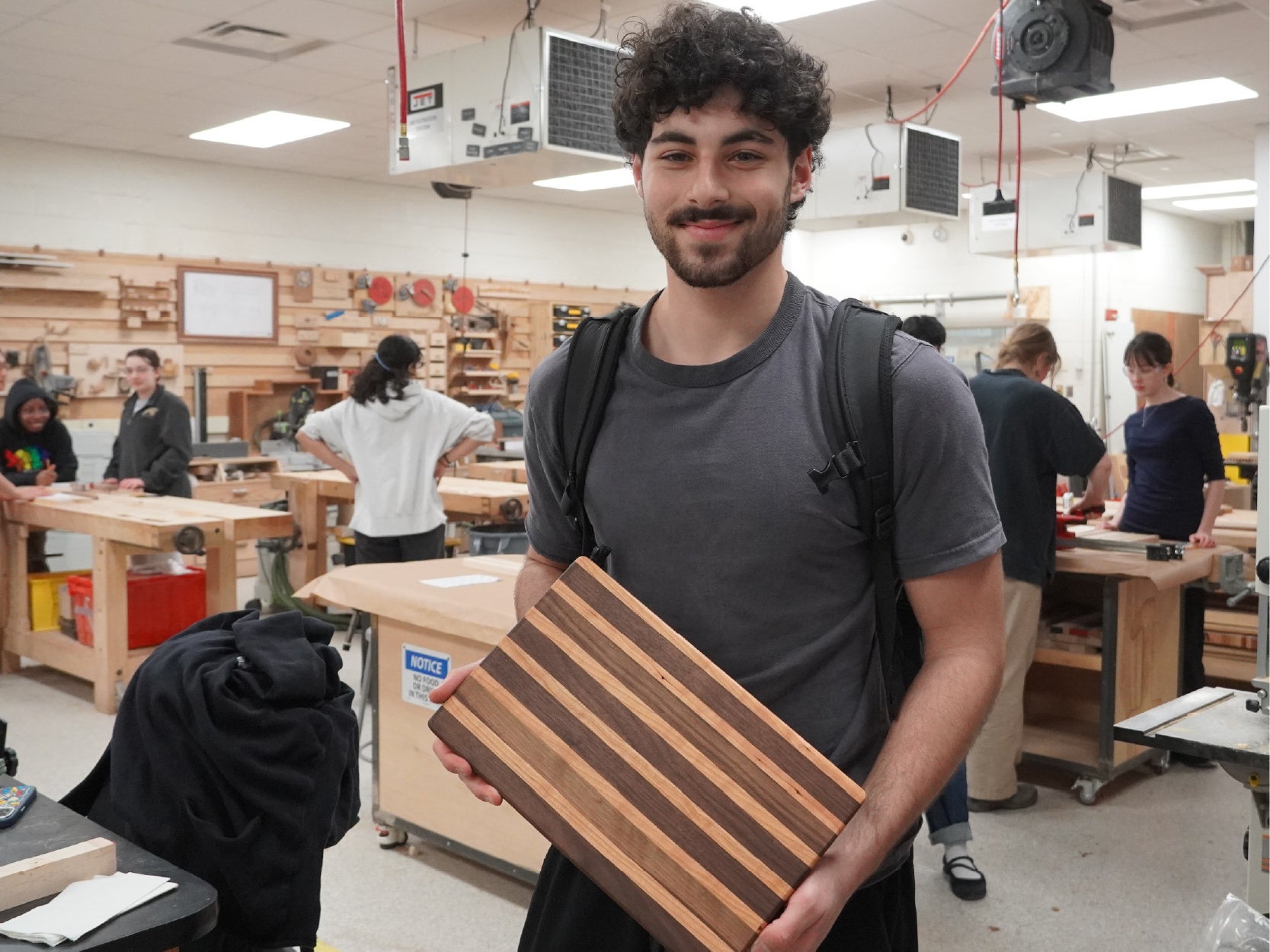 A photo of a student holding up a cutting board project made in the keystone woodshop.